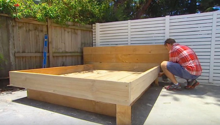 Мужчина строит кровать посреди двора.
