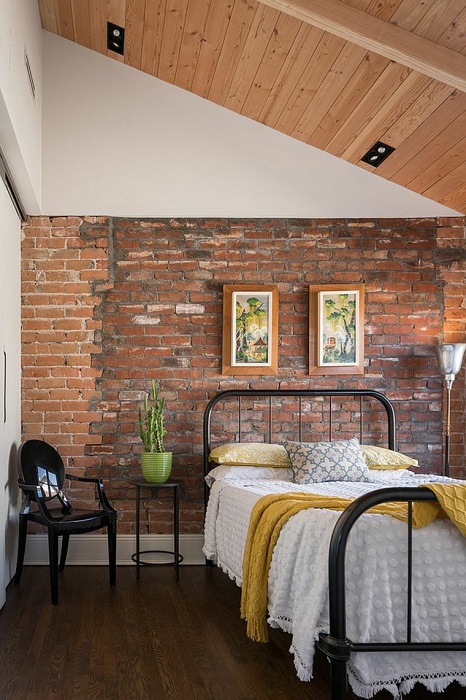Декорирование стен кирпичом выгодно подчёркивает высокие потолки спальни.