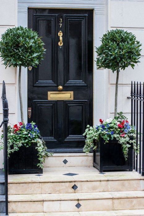 Вход в дом, оформленный парой оригинальных вазонов по обе стороны дверей.