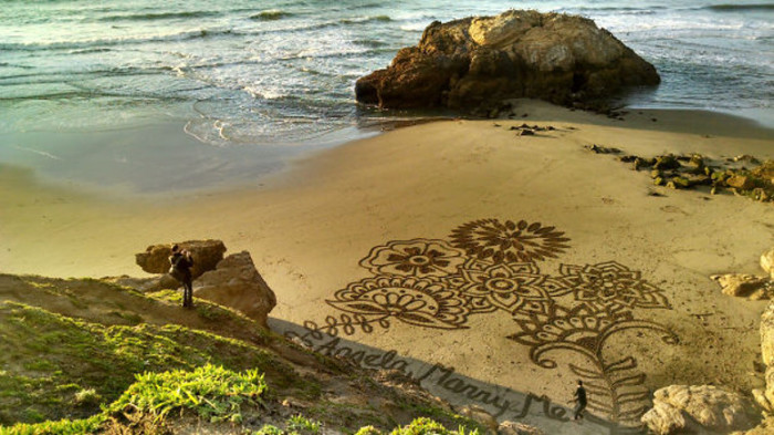 Оригинальное предложение руки и сердца с помощью красивого рисунка на песке.