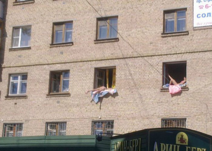 В солнечные деньки русские девушки загорают на подоконниках.